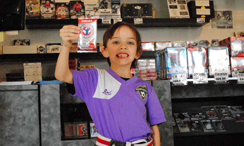 A child holding up a pack of hockey cards for National Hockey Card Day 2019