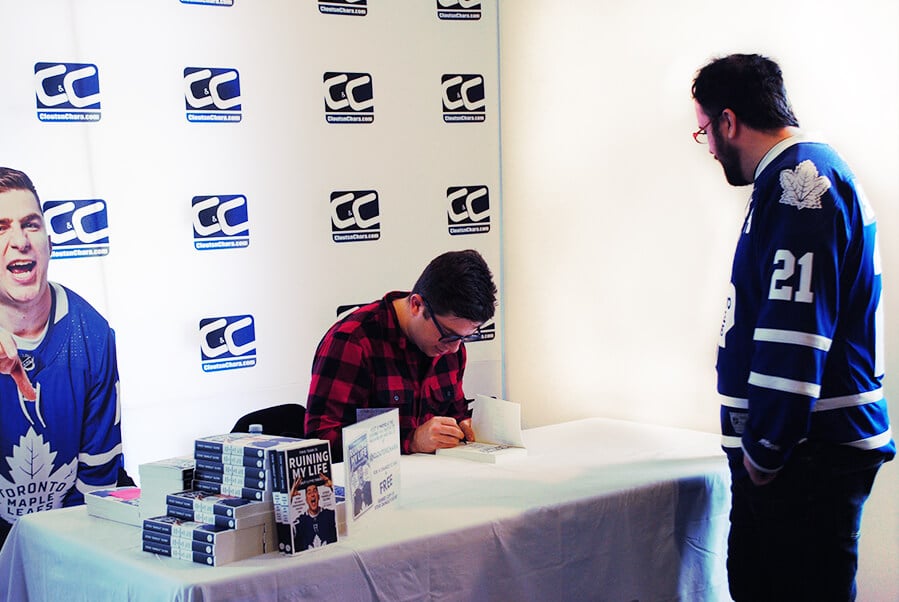 Steve Dangle Glynn signing his book for a fan wearing a Toronto Maple Leafs jersey.